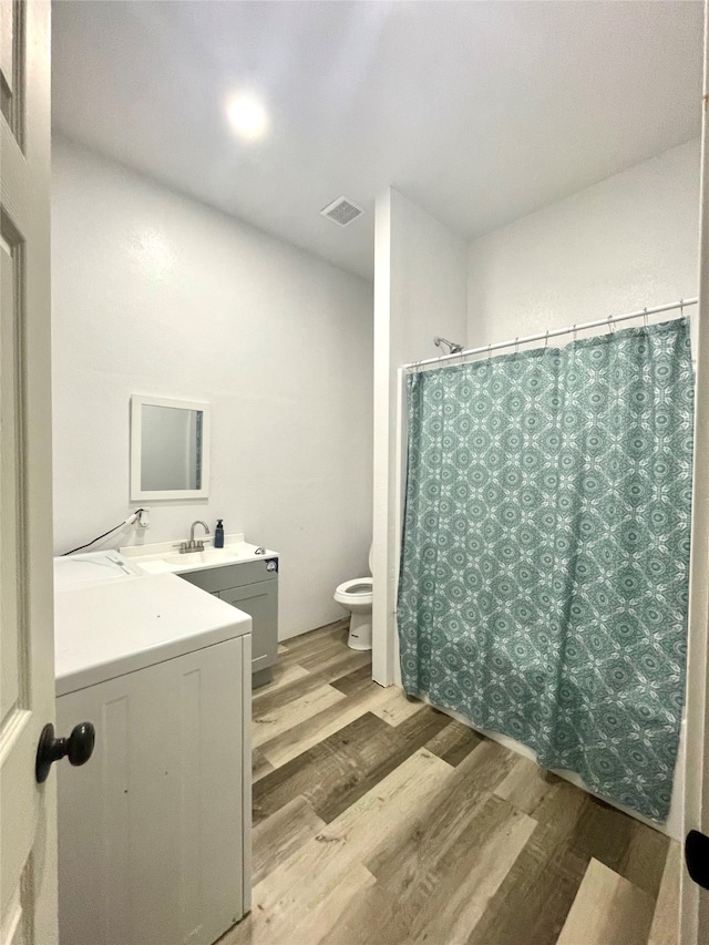 bathroom featuring washer / clothes dryer, toilet, hardwood / wood-style flooring, and vanity