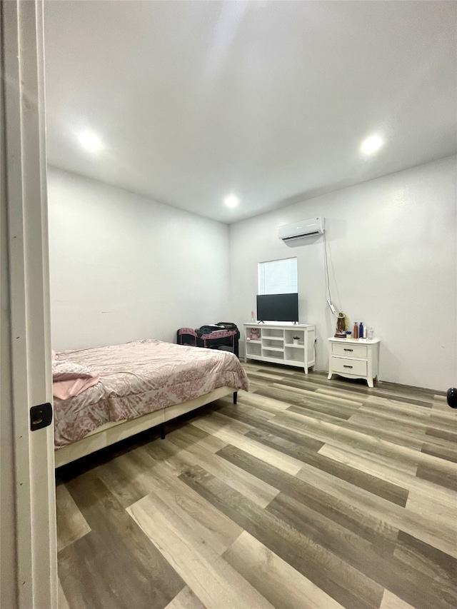 bedroom with hardwood / wood-style flooring and a wall mounted air conditioner