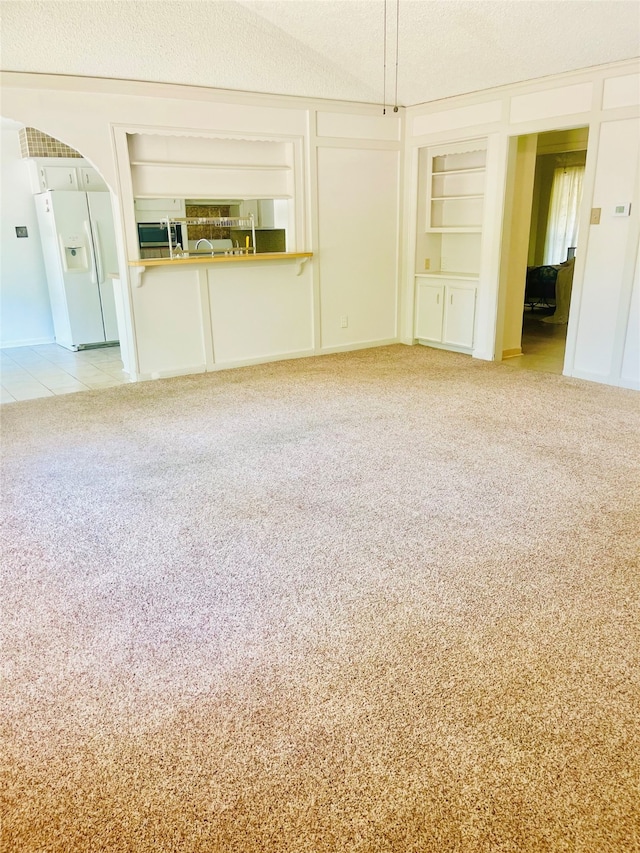 unfurnished living room with built in features, carpet flooring, and a textured ceiling