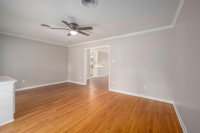 empty room featuring a textured ceiling, light hardwood / wood-style floors, ceiling fan, and ornamental molding