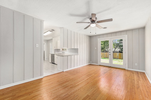 unfurnished living room featuring ceiling fan, french doors, a textured ceiling, and light wood-type flooring