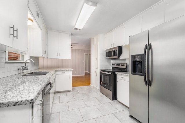 kitchen featuring backsplash, stainless steel appliances, ceiling fan, sink, and white cabinetry