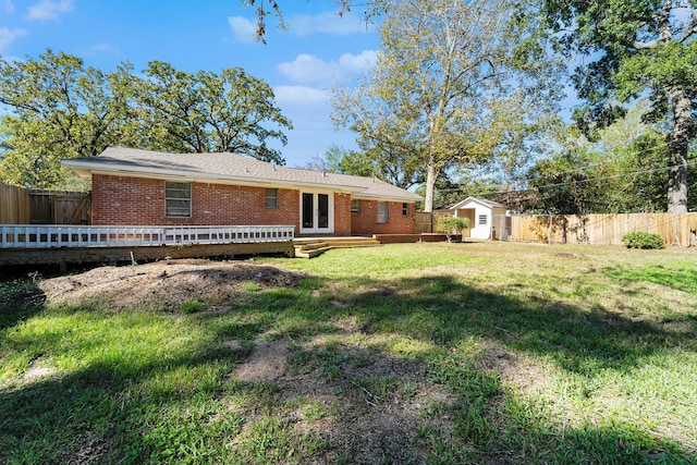 rear view of house featuring a yard, a storage unit, and a wooden deck