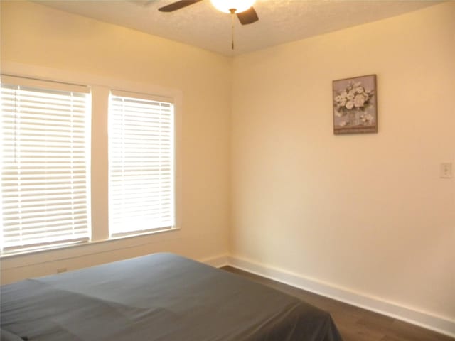 unfurnished bedroom with a ceiling fan, dark wood-style flooring, and baseboards