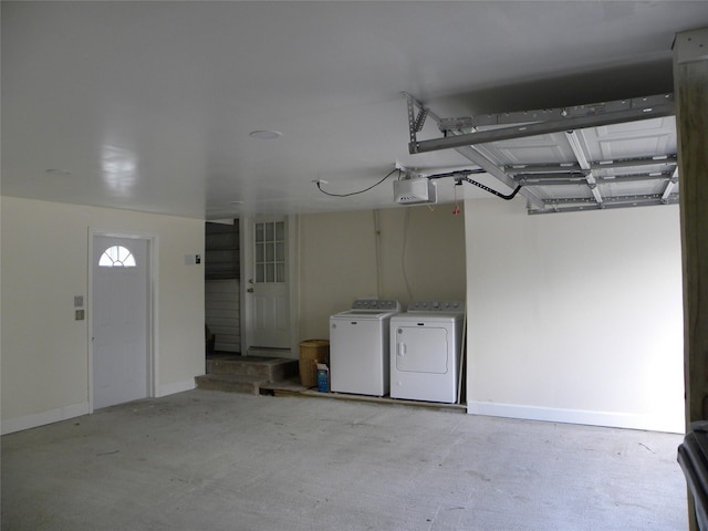 garage with a garage door opener, baseboards, and washing machine and clothes dryer