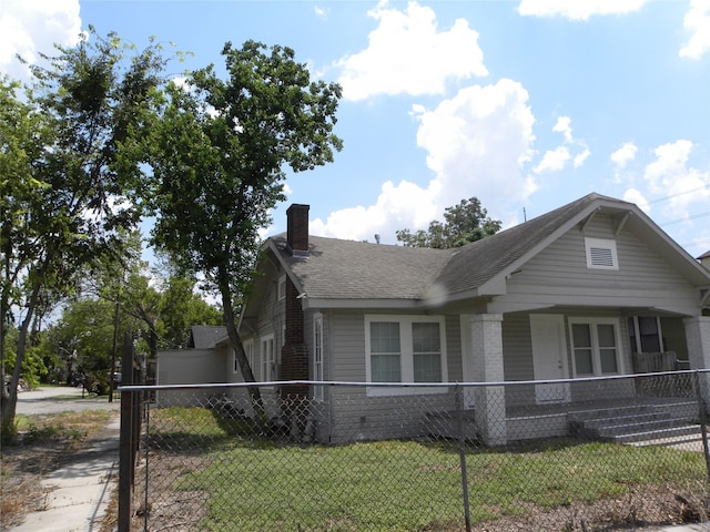 bungalow featuring brick siding, a fenced front yard, a chimney, covered porch, and a front yard