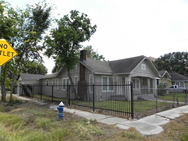 view of front facade with a fenced front yard, a chimney, and a front lawn