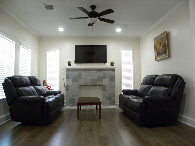 living room featuring a tile fireplace, crown molding, dark hardwood / wood-style flooring, and ceiling fan