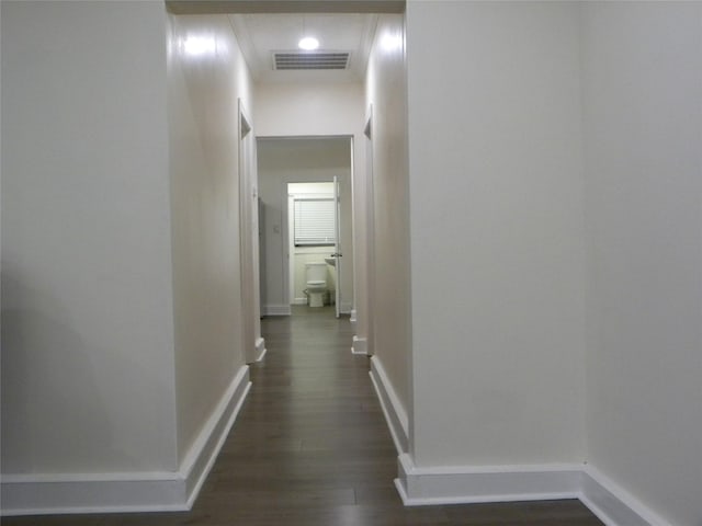 hallway featuring baseboards, visible vents, and dark wood-type flooring