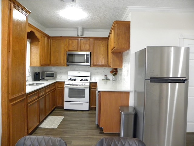 kitchen with ornamental molding, stainless steel appliances, a sink, and light countertops