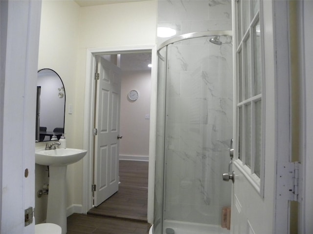 bathroom featuring baseboards, a sink, a marble finish shower, and wood finished floors