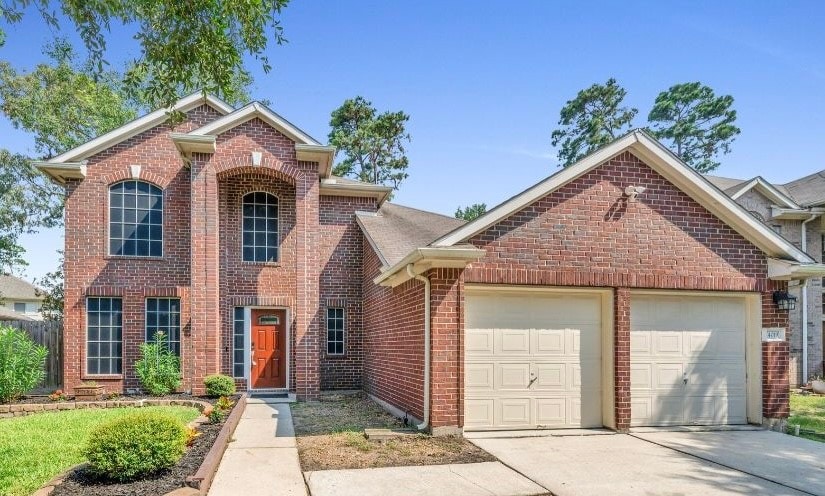 traditional home with a garage, brick siding, and concrete driveway