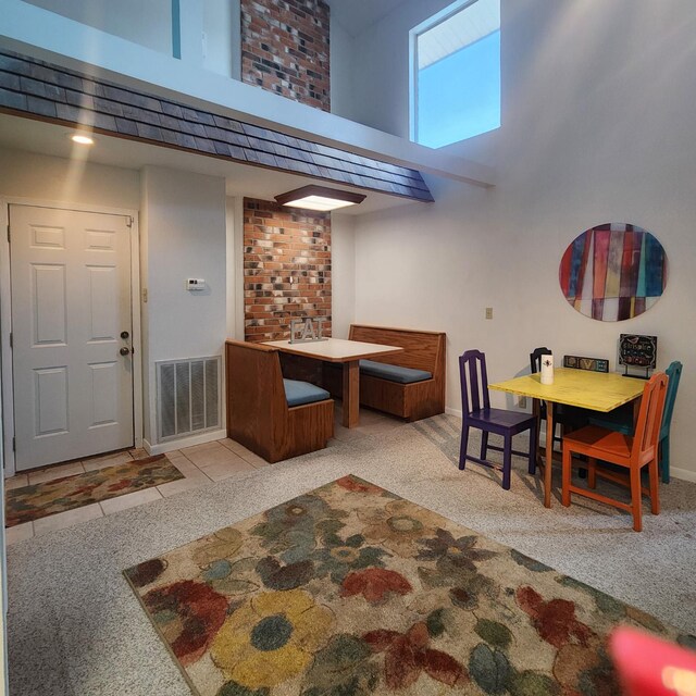 dining space featuring light colored carpet and a high ceiling