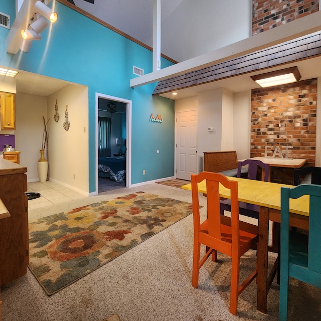 dining room with brick wall, light colored carpet, and a high ceiling