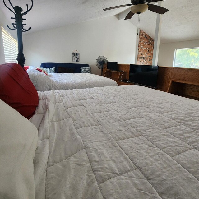 bedroom featuring ceiling fan, lofted ceiling, and a textured ceiling