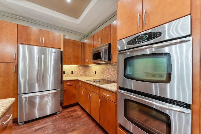 kitchen with light stone countertops, dark hardwood / wood-style flooring, stainless steel appliances, and backsplash