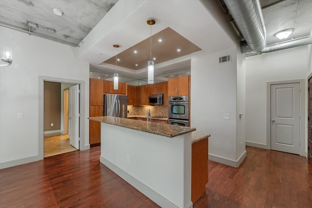 kitchen featuring tasteful backsplash, dark hardwood / wood-style floors, stainless steel appliances, and stone countertops