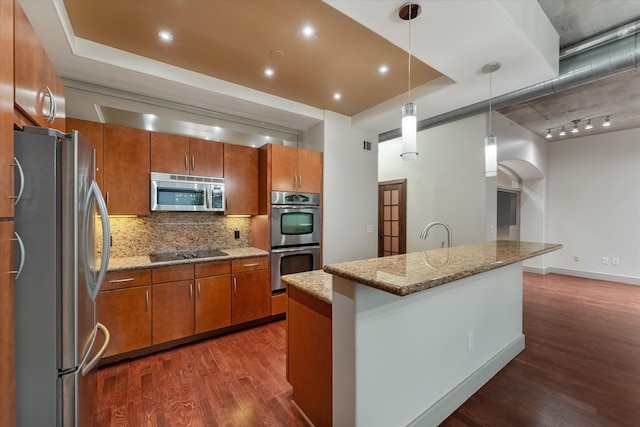 kitchen with dark hardwood / wood-style flooring, stainless steel appliances, backsplash, track lighting, and light stone counters