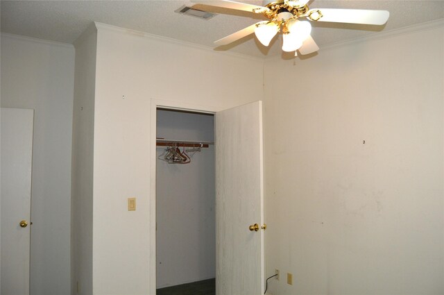 unfurnished bedroom featuring ceiling fan, a textured ceiling, ornamental molding, and a closet