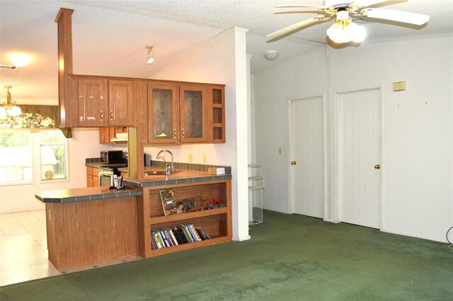 kitchen featuring ceiling fan with notable chandelier, lofted ceiling, kitchen peninsula, dark carpet, and sink