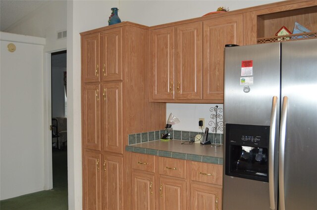 kitchen featuring stainless steel fridge with ice dispenser, tile counters, and carpet floors