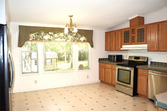 kitchen with appliances with stainless steel finishes, a wealth of natural light, pendant lighting, and ornamental molding