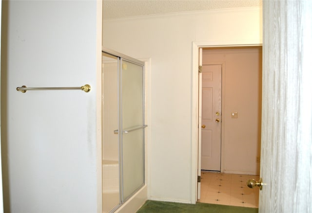 bathroom featuring a textured ceiling, an enclosed shower, tile patterned floors, and ornamental molding