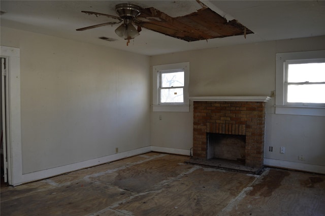 unfurnished living room featuring ceiling fan and a brick fireplace