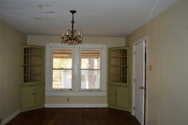 unfurnished dining area featuring a notable chandelier and dark hardwood / wood-style floors