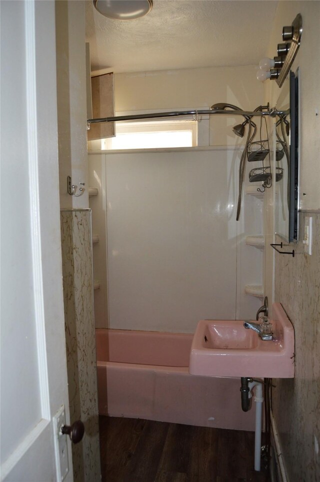 bathroom with sink, wood-type flooring, a textured ceiling, and bathtub / shower combination