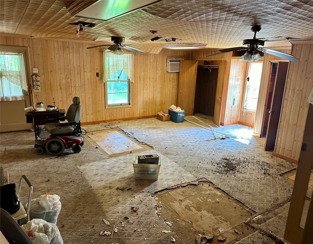 misc room featuring wood walls, plenty of natural light, and ceiling fan