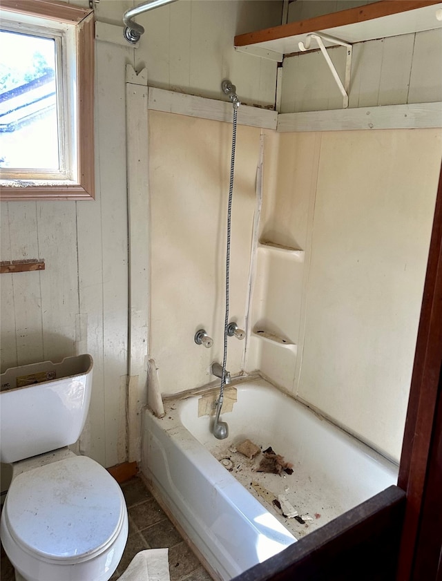 bathroom featuring wooden walls, shower / bathing tub combination, toilet, and tile patterned flooring