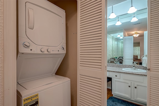 laundry area with stacked washing maching and dryer, sink, and a textured ceiling