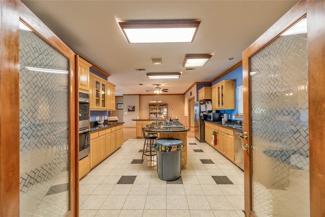 kitchen with a kitchen bar, light tile patterned floors, ornamental molding, a kitchen island, and stainless steel appliances