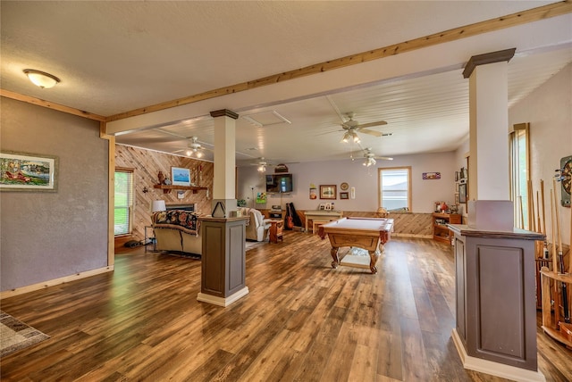 recreation room with ornate columns, dark hardwood / wood-style floors, a fireplace, and wood walls