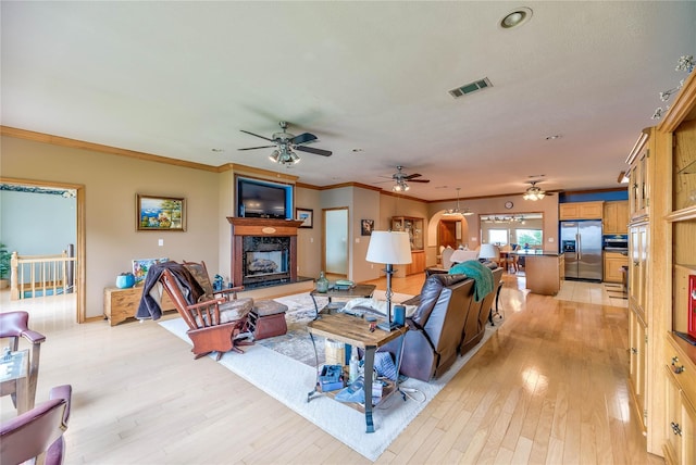 living room with a premium fireplace, crown molding, and light hardwood / wood-style flooring