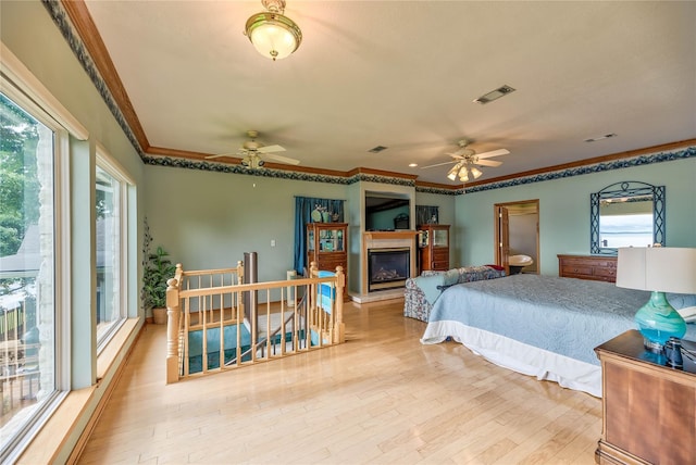 bedroom with multiple windows, crown molding, and light wood-type flooring