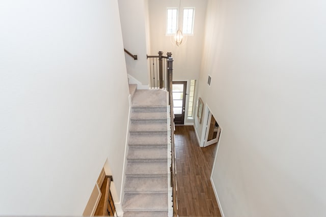 staircase featuring a high ceiling, plenty of natural light, and hardwood / wood-style floors