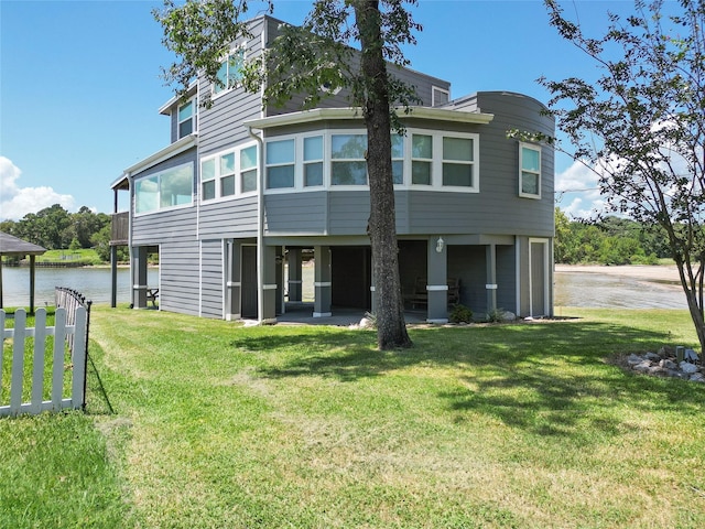 rear view of property featuring a water view, a yard, and a sunroom