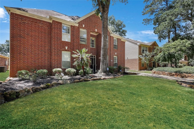 view of side of property featuring brick siding, a yard, and central air condition unit