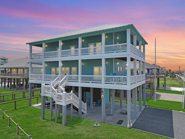 back house at dusk featuring a patio and a lawn