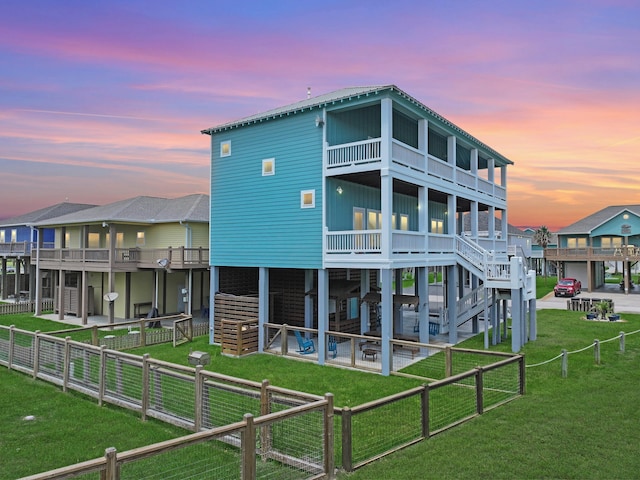 back house at dusk with a patio, a balcony, and a yard