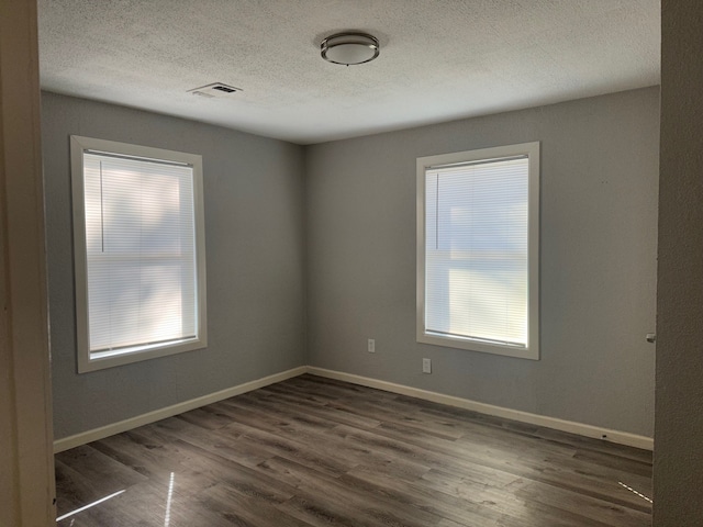 unfurnished room with wood-type flooring and a textured ceiling