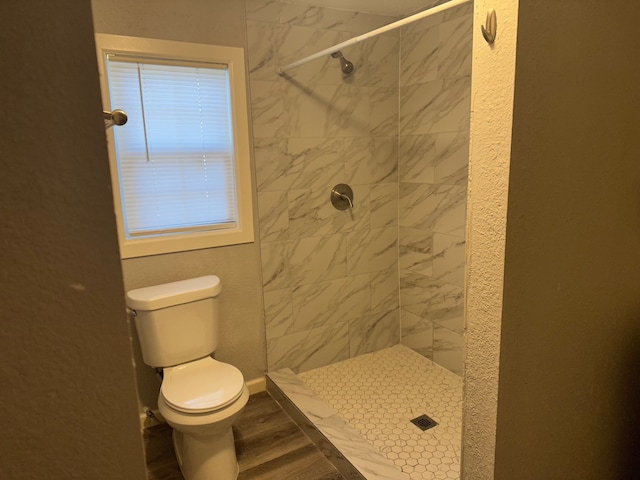 bathroom featuring tiled shower, hardwood / wood-style flooring, and toilet