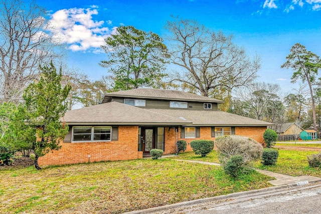 traditional-style home featuring a shingled roof, a front yard, and brick siding