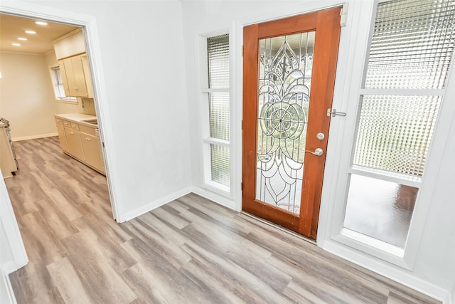 entrance foyer featuring ornamental molding and light hardwood / wood-style floors