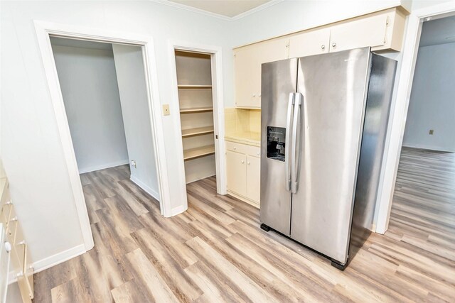 kitchen featuring stainless steel refrigerator with ice dispenser, cream cabinets, ornamental molding, and light hardwood / wood-style floors