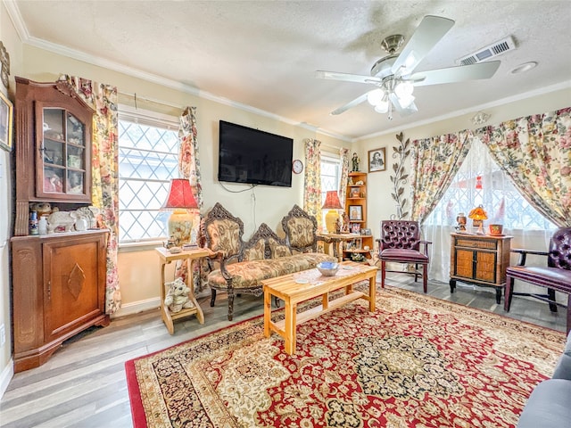 living room with ceiling fan, light hardwood / wood-style flooring, a textured ceiling, and crown molding