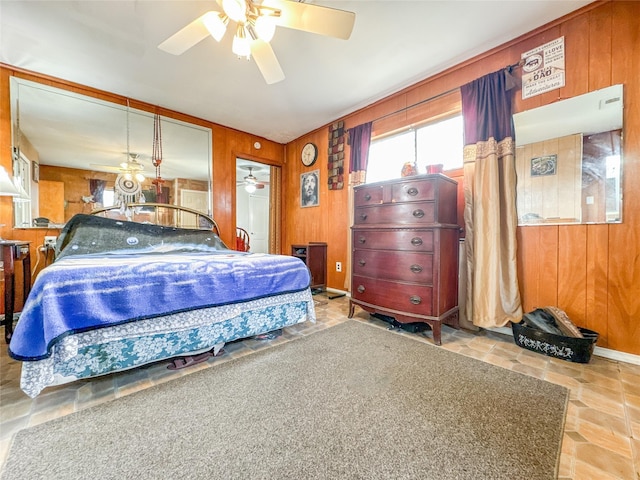 bedroom with a ceiling fan, stone finish flooring, and wood walls