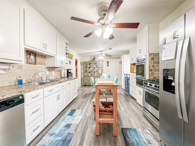 kitchen with light hardwood / wood-style flooring, stainless steel appliances, sink, ceiling fan, and decorative backsplash